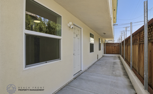 A long, narrow hallway with a white door and a window on the left side.